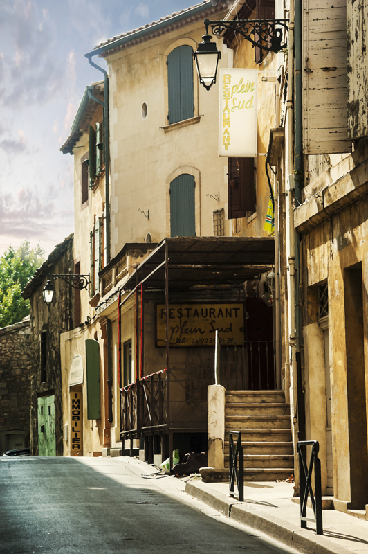 Typical street scene in Arles, Provence with an old Restaurant, given a paint effect.